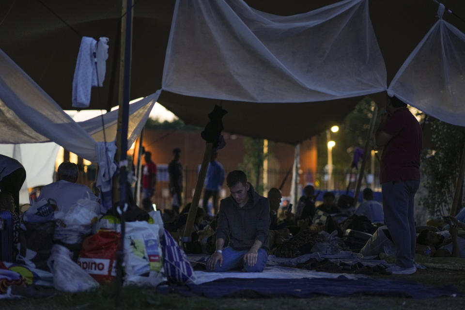 A man prays under a tarpaulin as hundreds of migrants who seek shelter prepared to spend the night outside an overcrowded asylum seekers center in Ter Apel, northern Netherlands, Thursday, Aug. 25, 2022. (AP Photo/Peter Dejong)