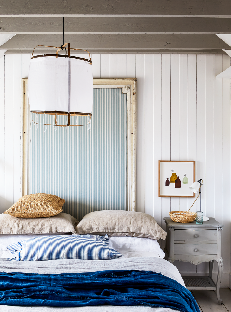 Coastal-inspired bedroom with a DIY headboard made from an antique mirror frame and striped upholstery for a nautical feel