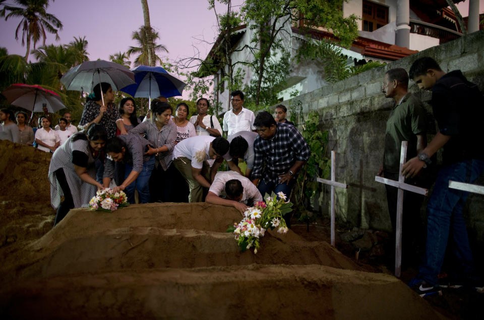 FILE - In this April 22, 2019, file photo, relatives place flowers after the burial of three victims of the same family, who died in an Easter Sunday bomb blast at St. Sebastian Church, in Negombo, Sri Lanka. On Easter Sunday, April 21, bombs shattered the celebratory services at two Catholic churches and a Protestant church in Sri Lanka. (AP Photo/Gemunu Amarasinghe, File)