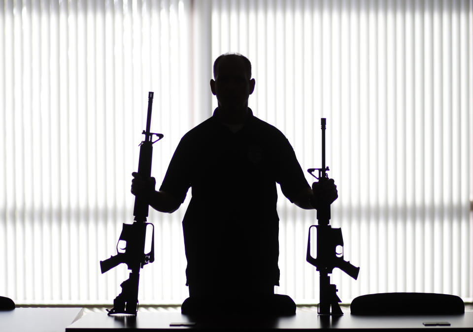 FILE - In this Aug. 29, 2017, file photo, an ATF agent poses with homemade rifles, or "ghost guns," at an ATF field office in Glendale, Calif. California's attorney general is suing the Trump administration in an effort to crack down on so-called "ghost guns" that can be built from parts with little ability to track or regulate the owner. (AP Photo/Jae C. Hong, File)