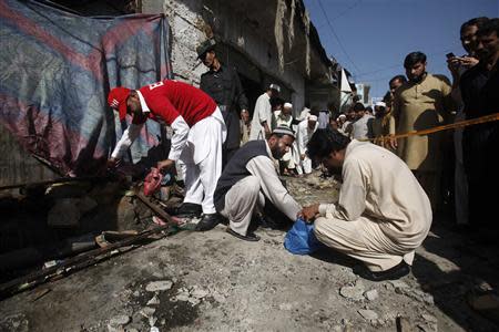 Security officials and rescue workers collect evidence at the site of a bomb blast in Charsadda district in the outskirts of Peshawar April 22, 2014. REUTERS/Fayaz Aziz