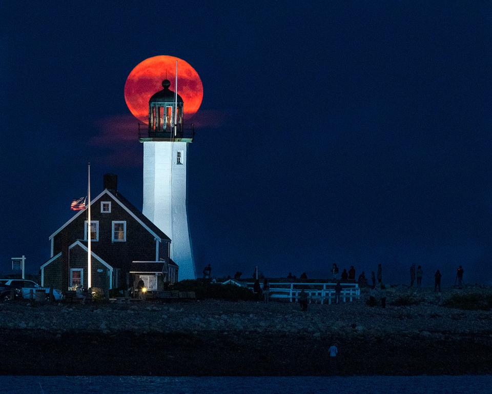 People gather at the foot of Scituate Lighthouse to check out the Harvest moon rising behind it on Thursday, Oct. 1, 2020. 