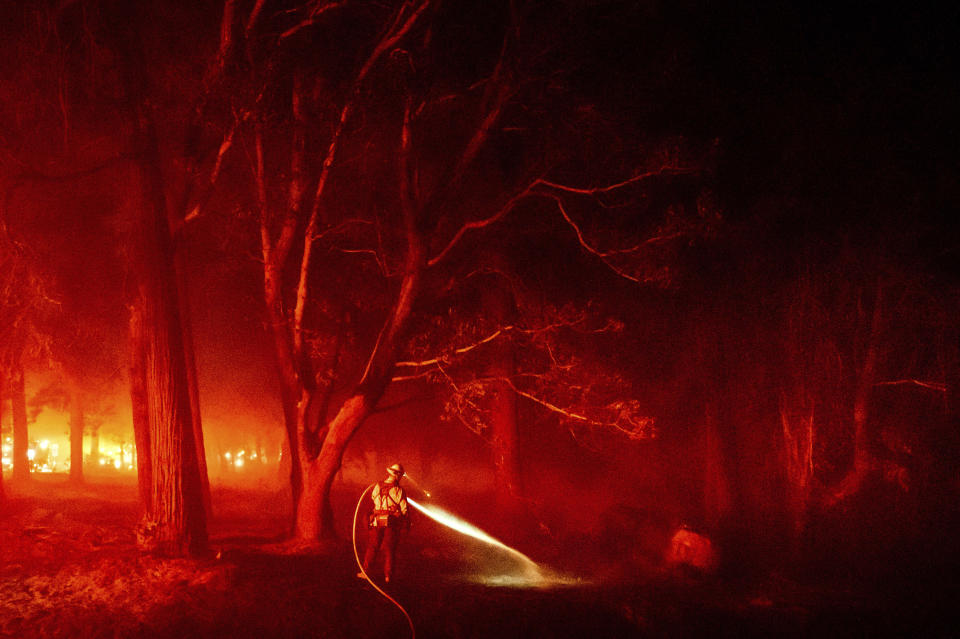 A firefighter hoses down hotspots along Foresthill Rd. as the Mosquito Fire burns in the Foresthill community of Placer County, Calif., on Tuesday, Sept. 13, 2022. (AP Photo/Noah Berger)