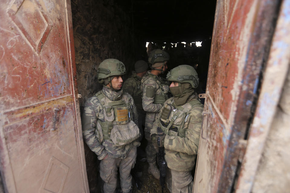 Turkish soldiers stand in a house in the countryside in the Syrian province of Idlib, Monday, Feb. 10, 2020. Turkey said it hit back at Syrian government forces on Monday, after "intense" Syrian shelling killed five of its soldiers and wounded five others in Syria's northern Idlib province. (AP Photo/Ghaith Alsayed)