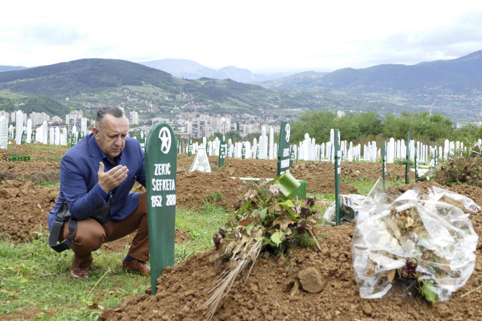 Tarik Svraka visits the graves of his parents in law, who died of COVID-19 related complications, in Zenica, Bosnia, Monday, Sept. 28, 2020. The coronavirus skeptics and rebels in Bosnia grow louder in step with the rising number of infections in the country. Recently, several families who lost their loved ones to COVID-19 were confronted online, and some even in real life, by scores of random virus believers and deniers sifting through their pain and questioning their relatives’ cause of death. (AP Photo/Almir Alic)