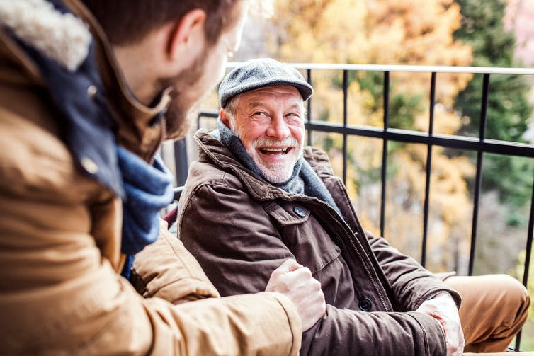 Old and young man sat talking outside