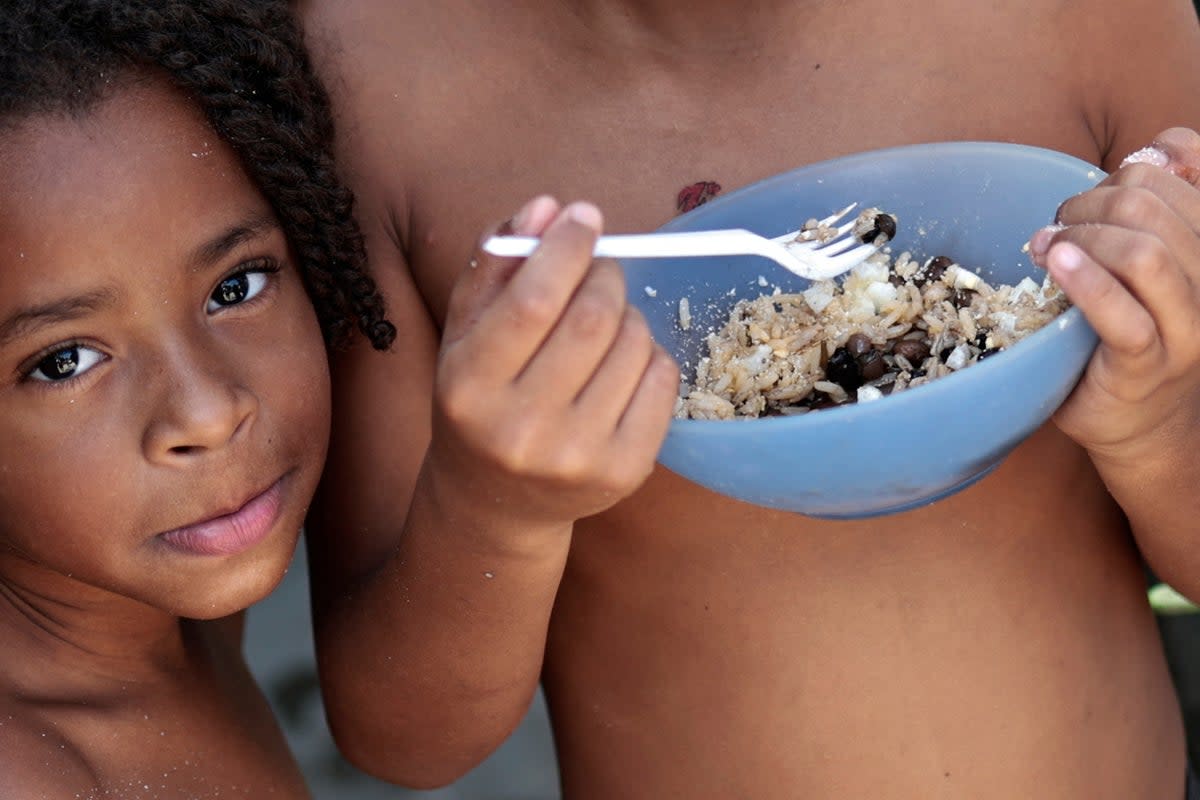 Thawanny Silva de Souza, 6, and Rafael Silva de Souza, 9, eat a lunch of rice, beans and egg in their family’s house, in the Arco Iris favela in Recife, Brazil (Reuters)