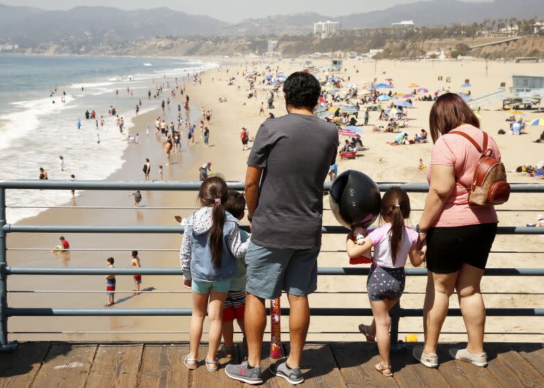 SANTA MONIA, CA - MARCH 29: Jose Rivera with wife Stephanie Rivera watching their nieces and nephew, Ariel, Sophia and Ignacio Arminta as then visit the Santa Monica Pier as people take advantage of the warm weather during the COVID-19 Spring break in Southern California Monday. Santa Monica Pier and Promenade on Monday, March 29, 2021 in Santa Monia, CA. (Al Seib / Los Angeles Times).