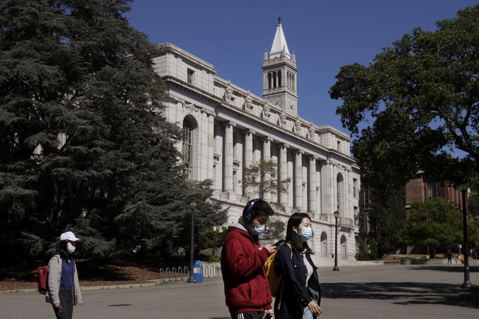 FILE - In this March 11, 2020, file photo, people wear masks while walking past Wheeler Hall on the University of California campus in Berkeley, Calif. Two of the nation's largest university systems say they intend to require COVID-19 vaccinations for all students, faculty and staff on University of California and California State University campuses this fall once the Food and Drug Administration gives formal approval, Thursday, April 22, 2021. (AP Photo/Jeff Chiu, File)