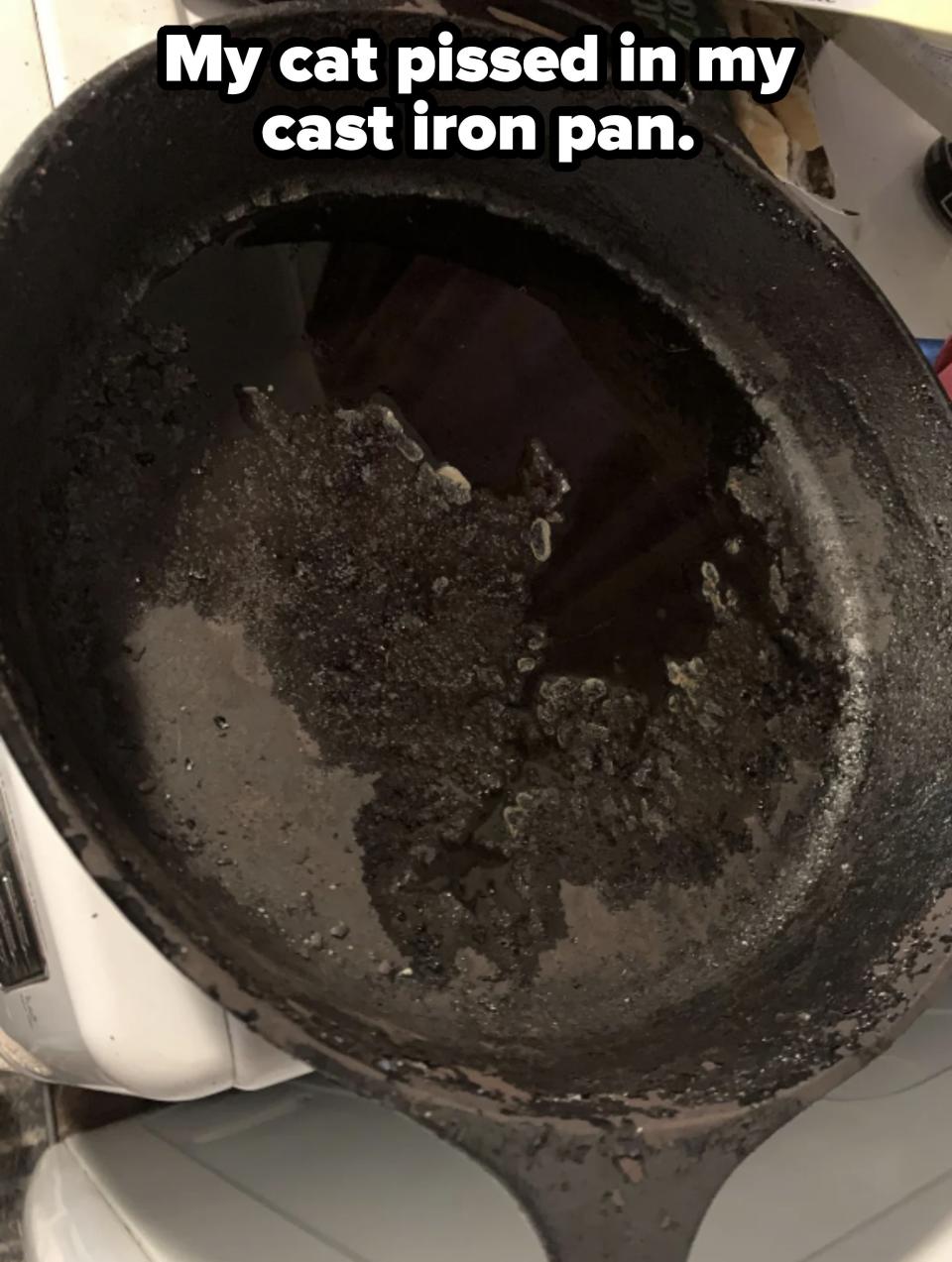 A worn and heavily used cast iron skillet with oil residue and signs of burnt food on its surface