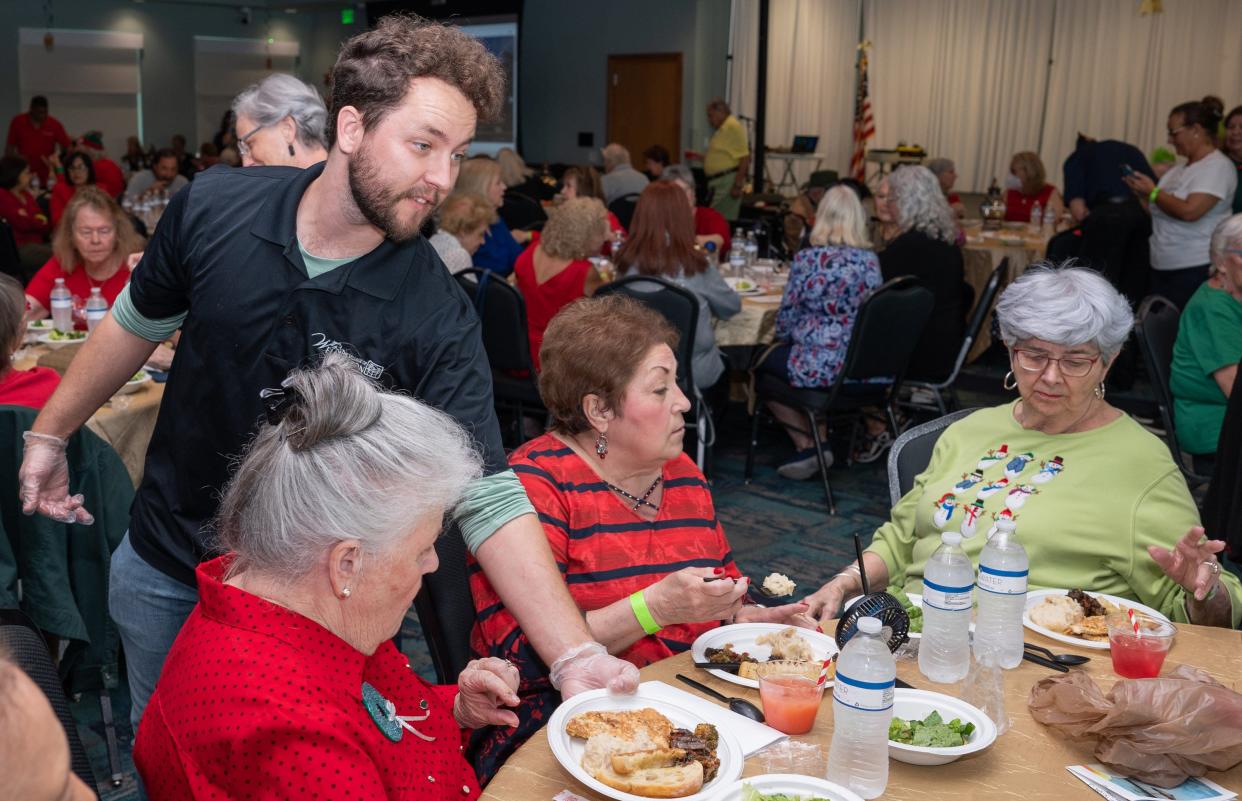 James Smith, a program coordinator at the Wellington Community Center, serves a plate of food during a holiday-themed luncheon on Tuesday, December 13, 2022, at the Wellington Community Center in Wellington, FL. Wellington Cares, together with the Wellington Community Center, is planning to start a meals program that will provide senior guests with free daily meals at the center.