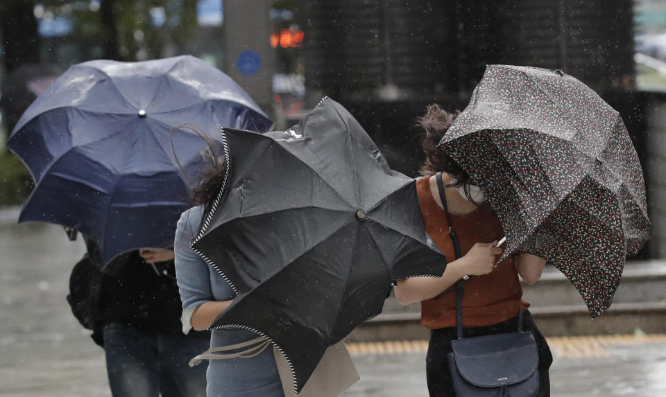 People struggle with their umbrellas against strong wind and rain in downtown Seoul, South Korea, Thursday, Sept. 3, 2020. A powerful typhoon ripped through South Korea’s southern and eastern coasts with tree-snapping winds and flooding rains Thursday, knocking out power to thousands of homes. (AP Photo/Lee Jin-man)