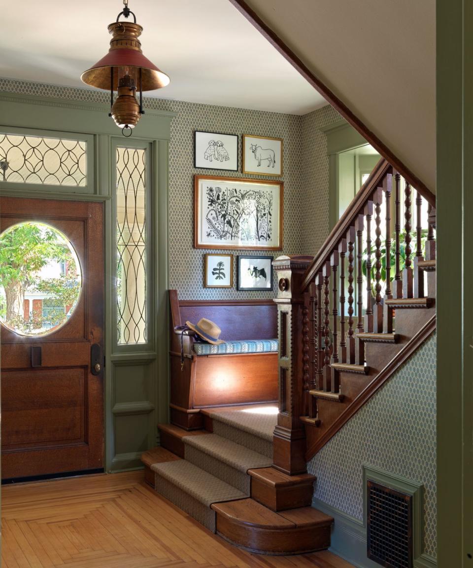 Green painted and wallpapered entryway with bench on steps