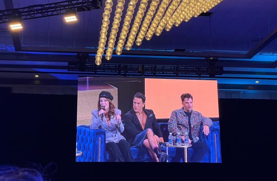 A big screen showing Lisa Vanderpump, Tom Sandoval, and Tom Schwartz