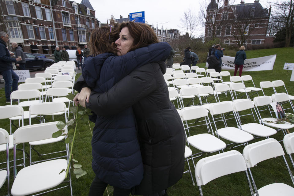 Silene Fredriksz-Hoogzand, right, who lost her son Bryce and his girlfriend Daisy, picture on chair far right, is hugged when standing amidst 298 empty chairs, each chair for one of the 298 victims of the downed Malaysia Air flight MH17, placed in a park opposite the Russian embassy in The Hague, Netherlands, Sunday, March 8, 2020. A missile fired from territory controlled by pro-Russian rebels in Ukraine in 2014, tore the MH17 passenger jet apart killing all 298 people on board. United by grief across oceans and continents, families who lost loved hope that the trial which starts Monday March 9, 2020, will finally deliver them something that has remained elusive ever since: The truth. (AP Photo/Peter Dejong)