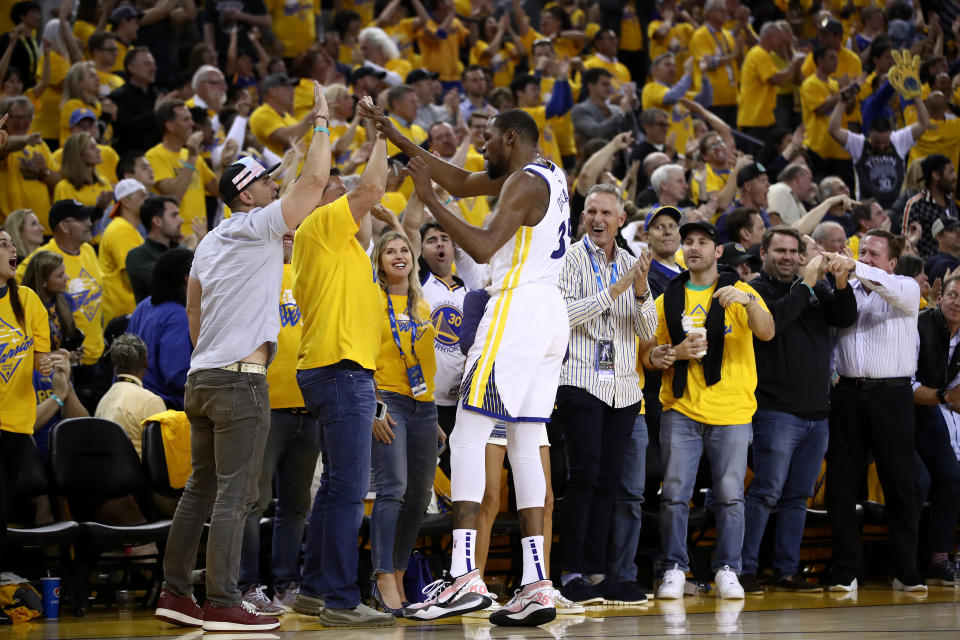 OAKLAND, CALIFORNIA - MAY 08:   Kevin Durant #35 of the Golden State Warriors high-fives the fans after the Warriors scored a basket against the Houston Rockets during Game Five of the Western Conference Semifinals of the 2019 NBA Playoffs at ORACLE Arena on May 08, 2019 in Oakland, California.  NOTE TO USER: User expressly acknowledges and agrees that, by downloading and or using this photograph, User is consenting to the terms and conditions of the Getty Images License Agreement.  (Photo by Ezra Shaw/Getty Images)