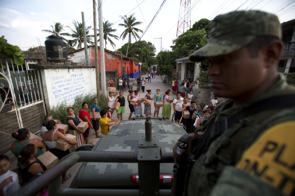 <p>A soldier looks on as housewives stand in line for rations and water in Juchitan, Oaxaca state, Mexico, a zone heavily affected by Thursday’s magnitude 8.1 earthquake, Saturday, Sept. 9, 2017. The boxes contained a mix of common Mexican household dried goods, including beans, corn flour, rice, powdered milk, tuna, hot chocolate, and and either jalapeno peppers or spicy sauce. (AP Photo/Rebecca Blackwell) </p>