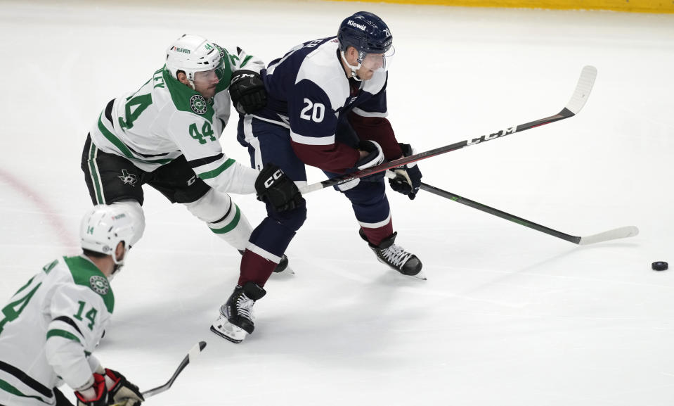 Colorado Avalanche center Lars Eller, right, struggles to control the puck as Dallas Stars defenseman Joel Hanley (44) pursues with left wing Jamie Benn (14) in the third period of an NHL hockey game Saturday, April 1, 2023, in Denver. (AP Photo/David Zalubowski)