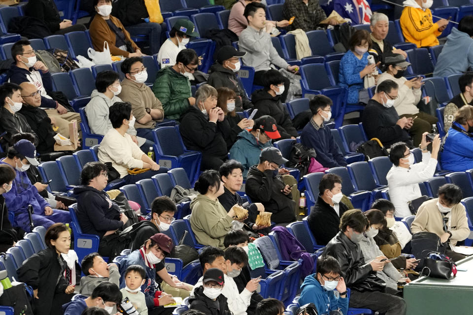 Spectators wearing face mask wait for a Pool B game between Australia and the Czech Republic at the World Baseball Classic at Tokyo Dome in Tokyo, Japan, Monday, March 13, 2023. The Japanese government relaxed its mask-wearing guidelines on Monday, but the vast majority of fans at the Tokyo Dome watching the World Baseball Classic still wore them. (AP Photo/Shuji Kajiyama)