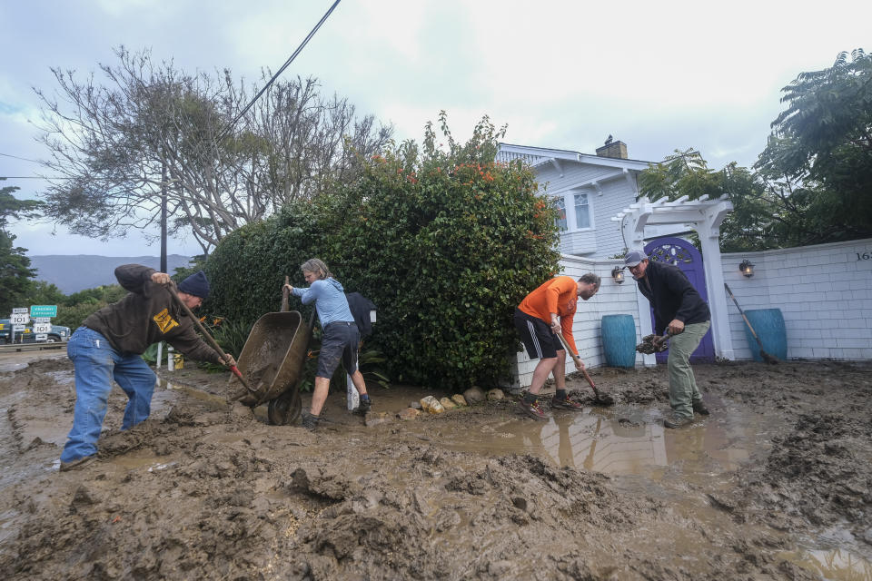 People shovel mud from the front of a home near Highway 101 in Montecito, Calif., Tuesday, Jan. 10, 2023. California saw little relief from drenching rains Tuesday as the latest in a relentless string of storms swamped roads, turned rivers into gushing flood zones and forced thousands of people to flee from towns with histories of deadly mudslides. (AP Photo/Ringo H.W. Chiu)