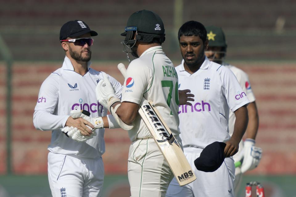 England's Ben Duckett, left, and teammate shake hand with Pakistan's Azhar Ali, center, who is playing his last match due to his retirement, after his dismissal during the third day of third test cricket match between England and Pakistan, in Karachi, Pakistan, Monday, Dec. 19, 2022. (AP Photo/Fareed Khan)