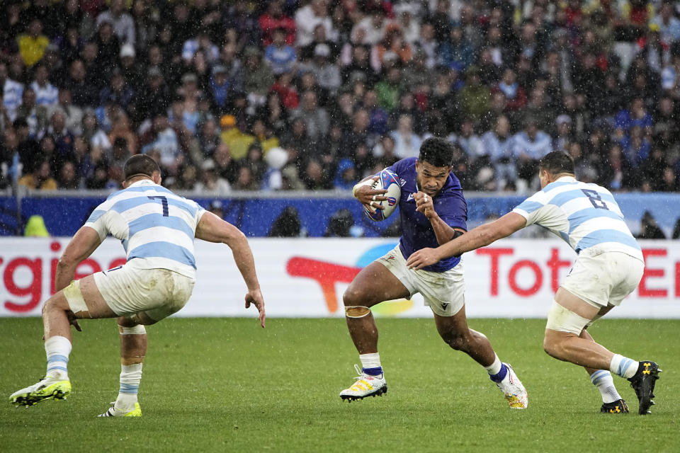 Samoa's Tumua Manu, centre, runs with the ball as he avoids a tackle by Argentina's Juan Martin Gonzalez, right, during the Rugby World Cup Pool D match between Argentina and Samoa at the Stade Geoffroy Guichard in Saint-Etienne, France, Friday, Sept. 22, 2023. (AP Photo/Laurent Cipriani)