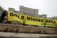 Greenpeace activists hold a banner in the yard of Romania's Parliament, during a protest against a Canadian company's plan to set up Europe's biggest open-cast gold mine in Romania, in Bucharest December 9, 2013. A special Romanian parliament commission overwhelmingly rejected a draft bill that would have allowed Canada's Gabriel Resources to set up Europe's biggest open-cast gold mine in the small Carpathian town of Rosia Montana last month. However, parliament plans to revise a mining law that could open way for the project. REUTERS/Bogdan Cristel (ROMANIA - Tags: ENVIRONMENT SOCIETY CIVIL UNREST BUSINESS)