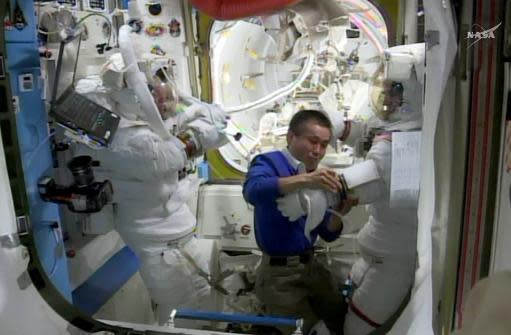 Foto tomada de imagen de la NASA TV el 23 de abril de 2014 muestra al astronauta japonés de la Estación Espacial Internacional (ISS) Koichi Wakata(C) asistiendo a su compañeros estadounidenses Steve Swanson(I) y Rick Mastracchio dentro de la nave luego de un paseo para reparar una computadora. (NASA TV/AFP | HANDOUT)