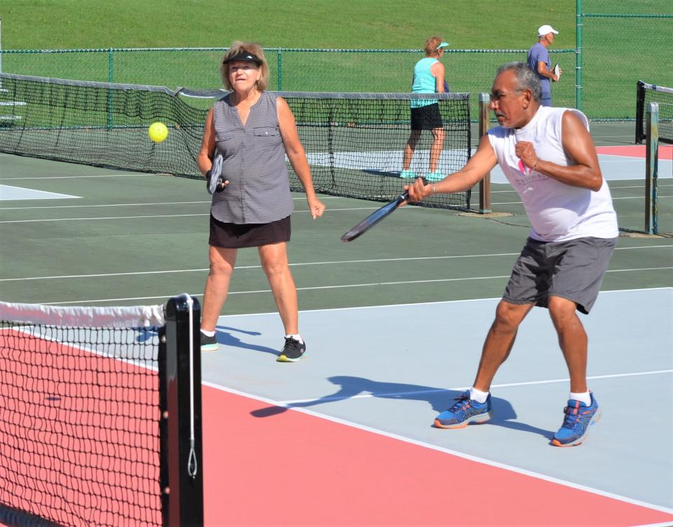 Mike Luna returns a serve as teammate Joyce Knight looks on during a pickleball match. The Battle Creek Pickleball Club plays several times a week at the refurbished courts at Kellogg Community College.