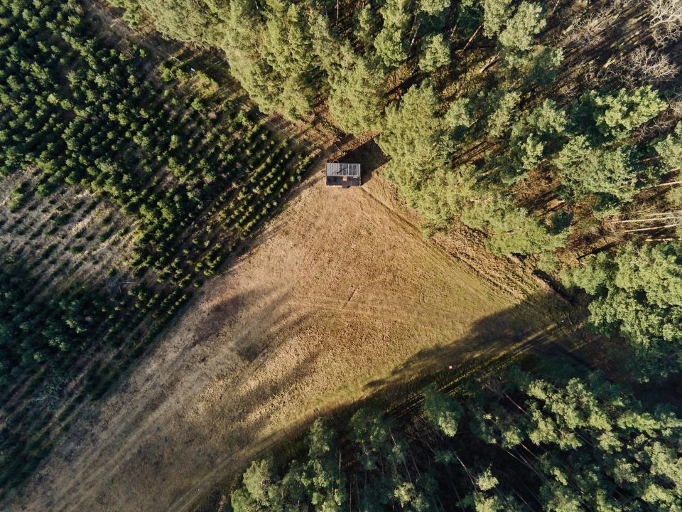 An overhead view of a Raus cabin in nature surrounded by trees and open fields.