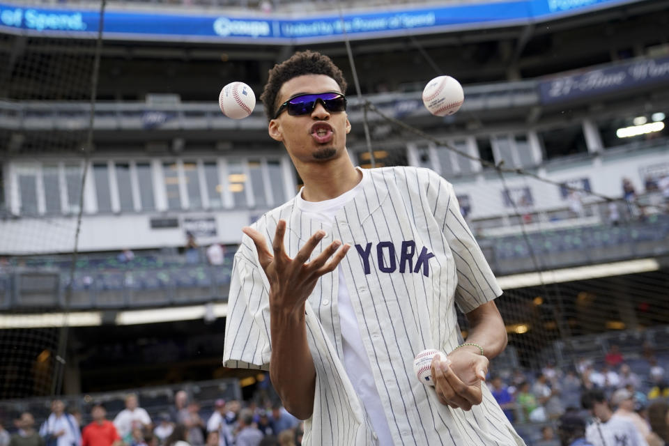 Victor Wembanyama, a projected first-round NBA draft pick, juggles baseballs before throwing the ceremonial first pitch before a baseball game between the New York Yankees and the Seattle Mariners, Tuesday, June 20, 2023, in New York. (AP Photo/John Minchillo)