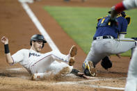 Miami Marlins' Brian Anderson, left, scores past Milwaukee Brewers catcher Omar Narvaez, right, on a single hit by Payton Henry during the second inning of a baseball game, Sunday, May 15, 2022, in Miami. (AP Photo/Lynne Sladky)