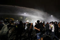 Police use water cannons to disperse pro-democracy protesters during a street march in Bangkok, Thailand Sunday, Nov. 8, 2020. The protesters continue to gather Sunday, led by their three main demands of Prime Minister Prayuth Chan-ocha's resignation, changes to a constitution that was drafted under military rule and reforms to the constitutional monarchy. (AP Photo/Sakchai Lalit)