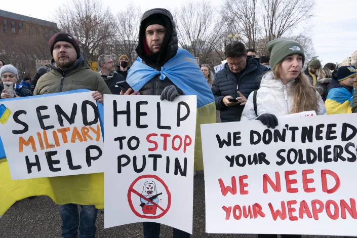 People hold signs reading: Send Military Help; Help to Stop Putin; and We Don't Need Your Soldiers, We Need Your Weapon.