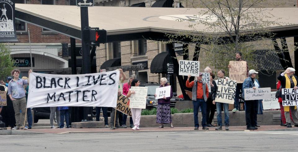 Approximately 50 demonstrators hold signs and wave to passersby in downtown Wooster last month, on the 700th consecutive day of protests since George Floyd's death.