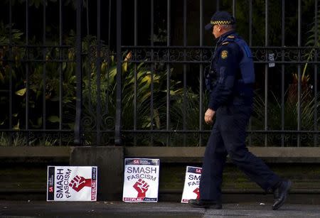 A policeman walks past placards discarded on a footpath outside the Victorian parliament building after protests in Melbourne, Australia, July 18, 2015. REUTERS/David Gray