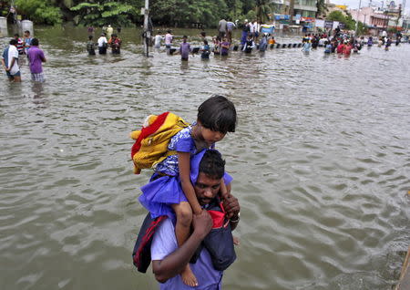 A man carries a girl through a flooded road in Chennai, India, December 2, 2015 REUTERS/Stringer