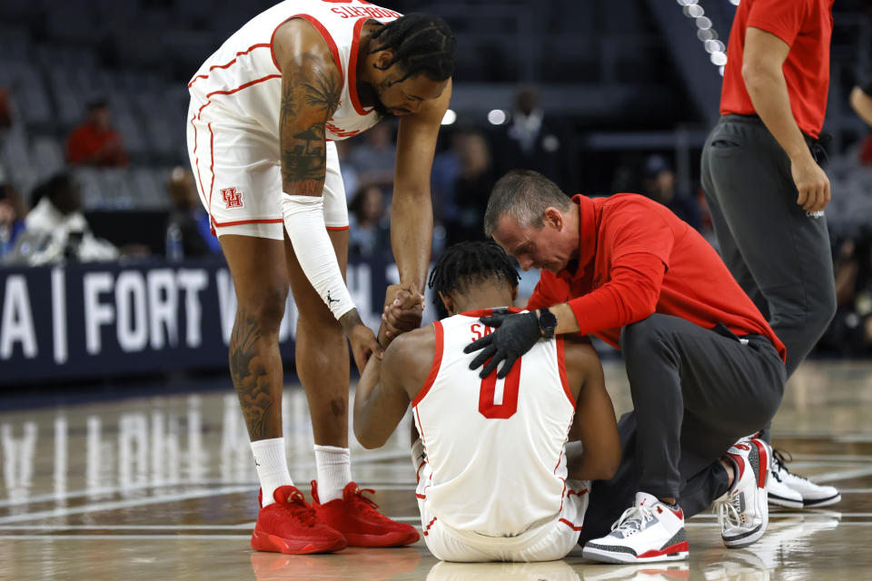 Houston forward Jarace Walker (25) and team staff attend to guard Marcus Sasser (0) after Sasser went down on the court against Cincinnati during the first half of an NCAA college basketball game in the semifinals of the American Athletic Conference Tournament, Saturday, March 11, 2023, in Fort Worth, Texas. (AP Photo/Ron Jenkins)