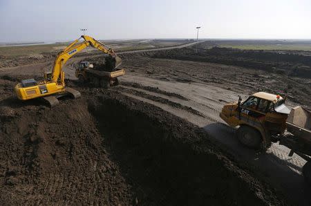 An excavator loads a lorry with earth from the Crossrail project which will be used to landscape a saltwater marsh wildlife habitat on Wallasea island, in Essex, March 13, 2014. REUTERS/Andrew Winning