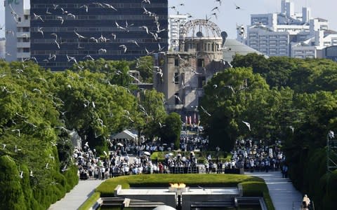 Doves fly over the Peace Memorial Park with the Atomic Bomb Dome in the background, at a ceremony in Hiroshima - Credit: Reuters