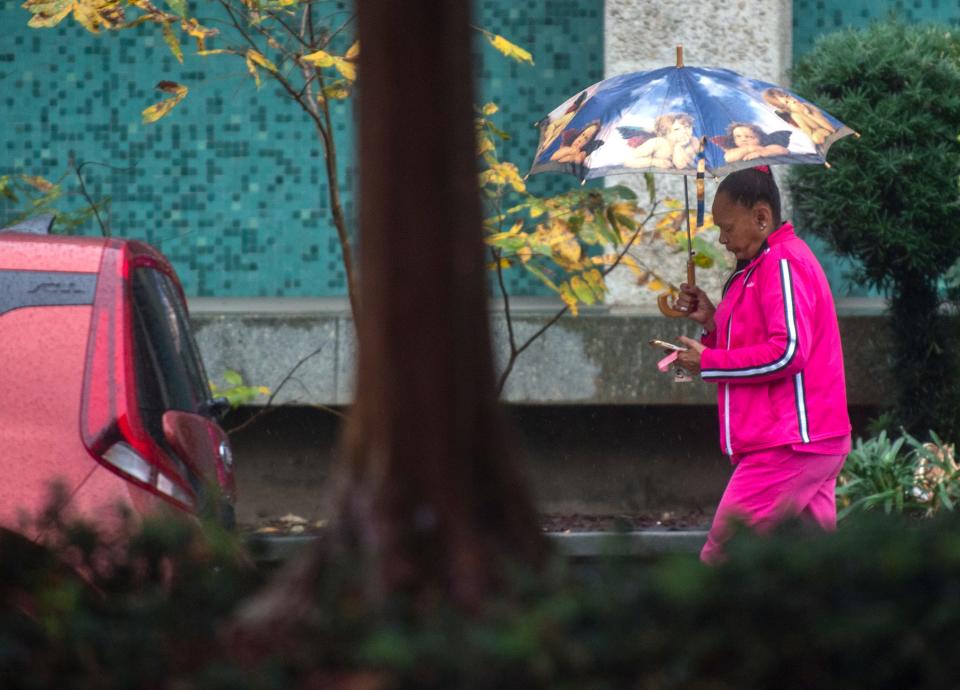 A woman uses an umbrella to keep dry from the first rain of the season as she walks down Weber Avenue near San Joaquin Street in downtown Stockton on Tuesday, Nov. 1, 2022.