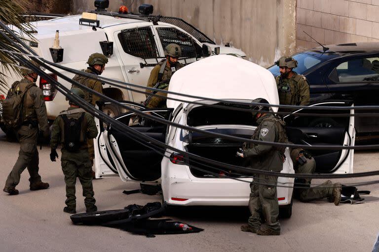 Las fuerzas de seguridad israelíes revisan un automóvil que supuestamente fue utilizado por un palestino para llevar a cabo un ataque frustrado contra tropas posicionadas cerca del asentamiento de Kiryat Arba en las afueras de la ciudad ocupada de Hebrón, en Cisjordania, el 1 de febrero de 2024, después de dispararle al sospechoso y arrestarlo para interrogarlo.
