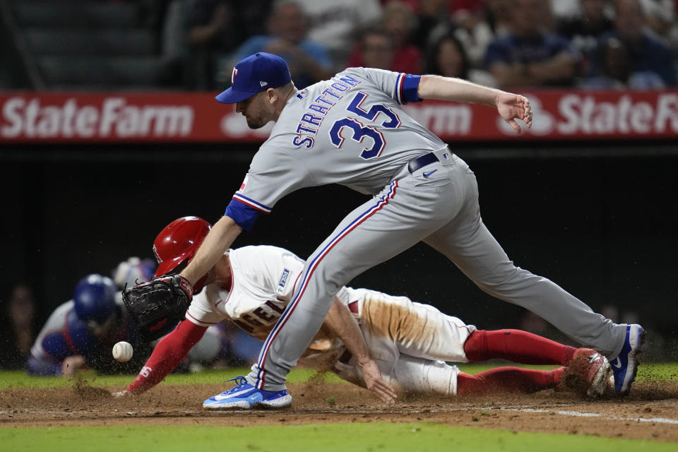 REMOVES REFERENCE TO EDUARDO ESCOBAR GROUNDING OUT - Los Angeles Angels' Randal Grichuk scores ahead of a throw to Texas Rangers relief pitcher Chris Stratton (35) after a wild pitch during the fifth inning of a baseball game in Anaheim, Calif., Tuesday, Sept. 26, 2023. (AP Photo/Ashley Landis)