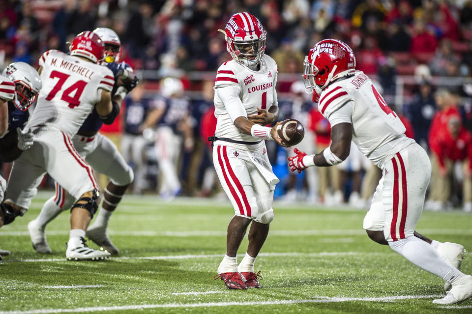 Louisiana-Lafayette quarterback Levi Lewis (1) hands the ball off to running back Montrell Johnson during an NCAA college football game against Liberty Saturday, Nov. 20, 2021, at Williams Stadium in Lynchburg, Va. (AP Photo/Kendall Warner)