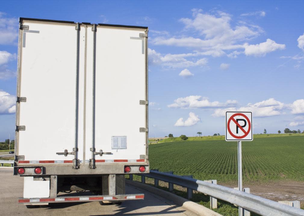 Back of parked, white semitruck by no parking sign.