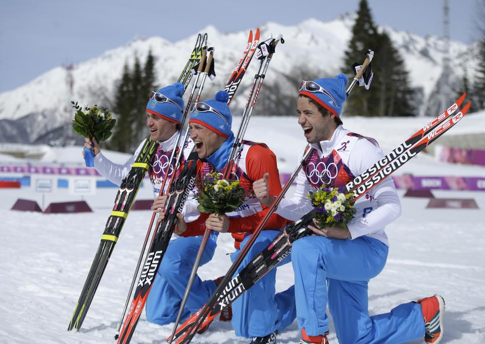 Russia's gold medal winner Alexander Legkov is flanked by Russia's silver medal winner Maxim Vylegzhanin, left and Russia's bronze medal winner Ilia Chernousov during the flower ceremony of the men's 50K cross-country race at the 2014 Winter Olympics, Sunday, Feb. 23, 2014, in Krasnaya Polyana, Russia. (AP Photo/Gregorio Borgia)