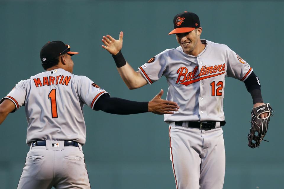 Baltimore Orioles' Stevie Wilkerson (12) celebrates with Richie Martin (1) after making the catch on a flyout by Boston Red Sox's Jackie Bradley Jr. during the eighth inning of a baseball game in Boston, Sunday, Sept. 29, 2019. (AP Photo/Michael Dwyer)