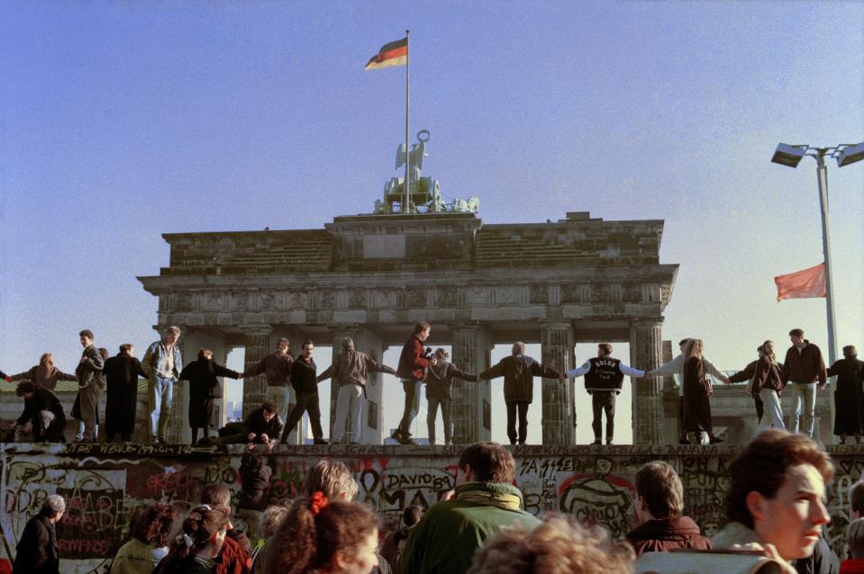 Berliners sing and dance on top of the Berlin wall to celebrate the opening of East-West German borders on Nov. 10, 1989. Thousands of East German citizens moved into the West after East German authorities opened all border crossing points to the West. In the background is the Brandenburg Gate.