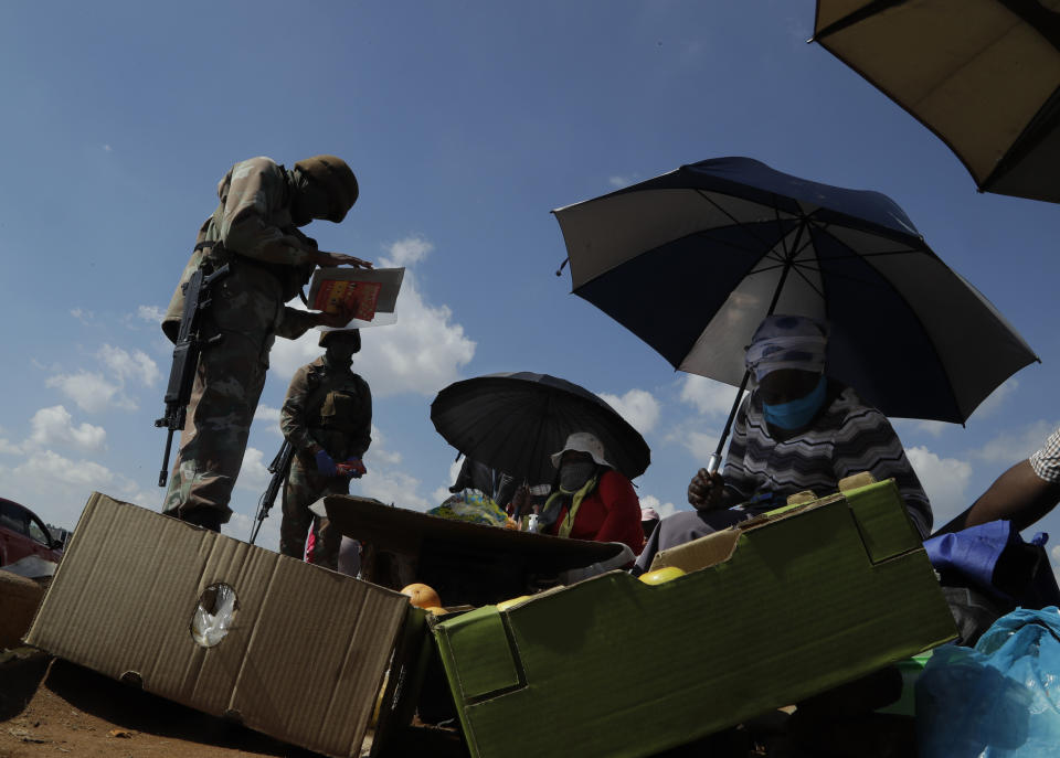 Soldiers check the permits of informal traders while on patrol in Soweto, South Africa, April 23, 2020, as the country remains in lockdown for a fourth week to combat the spread of the coronavirus. (AP Photo/Themba Hadebe)