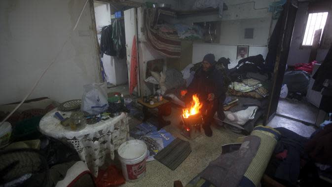 Seorang pria menghangatkan diri di sekitar api unggun di dalam kamar atapnya, di kota pelabuhan selatan Sidon, Lebanon, 19 Januari 2022. Badai salju di Timur Tengah telah membuat banyak warga Lebanon dan Suriah berebut mencari cara untuk bertahan hidup. (AP Photo/Mohammed Zaatari)